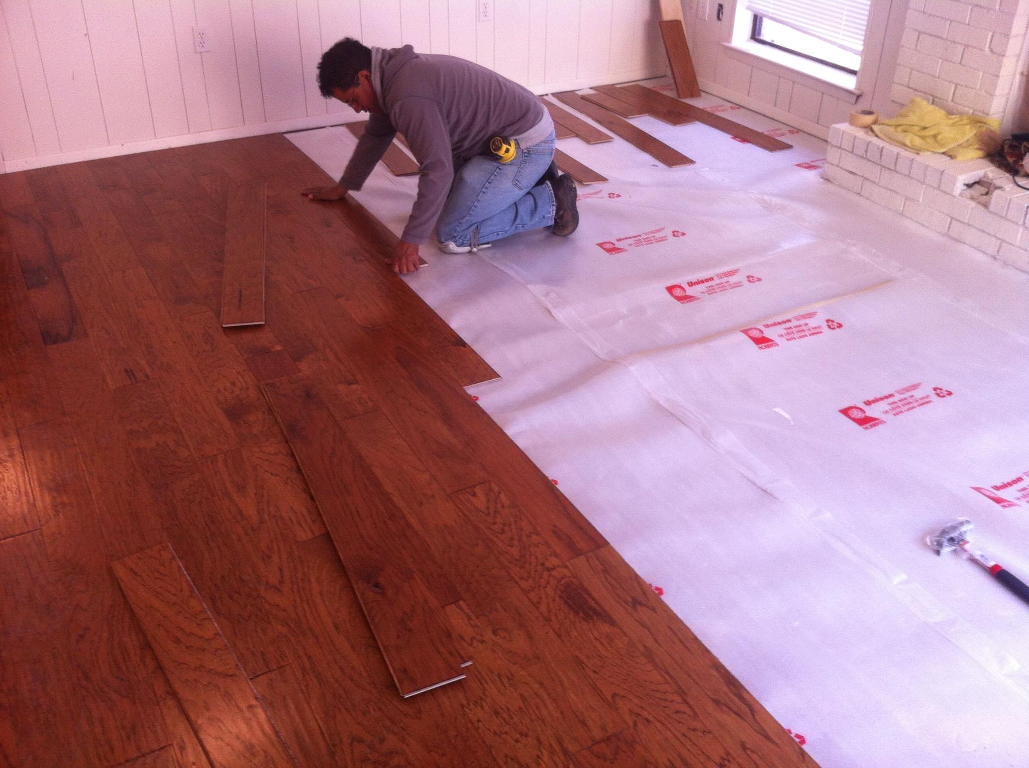 Hardwood flooring installation in progress — underlayment and planks being laid